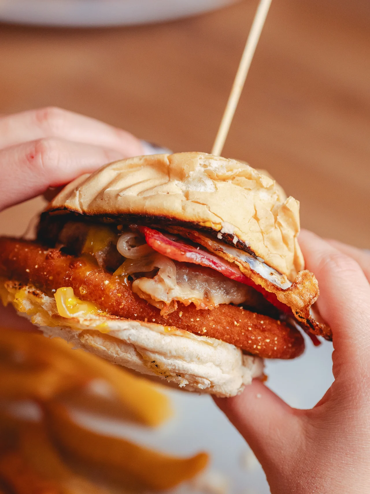 La hamburguesa Cheese Bomba de Oliva, servida con papas y sostenida entre las manos