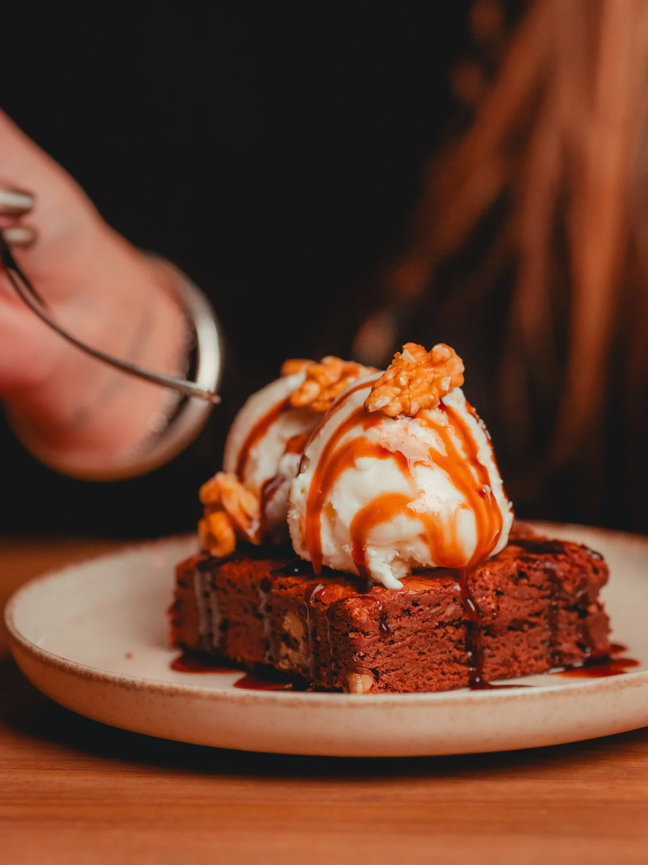 Brownie con helado, nueces y salsa en una mesa de Oliva